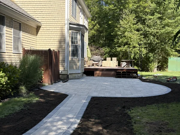 Curved paver patio with connecting walkway to deck by MAC Excavation & Landscape in South Shore MA