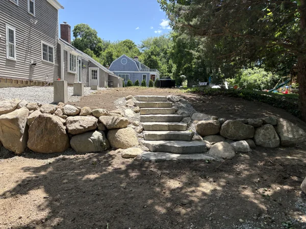 Boulder retaining wall with stone steps installation by MAC Excavation & Landscape in South Shore MA