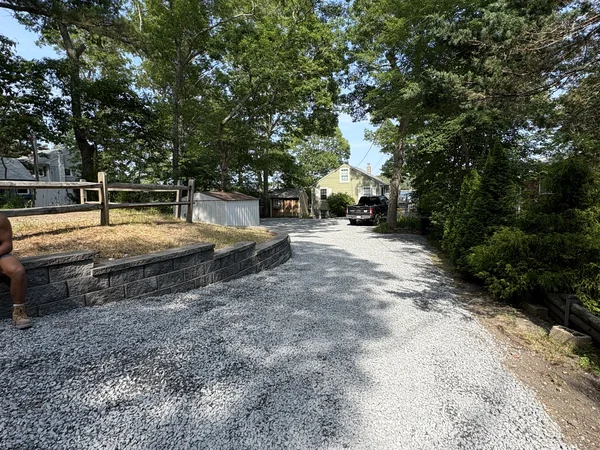 Graded gravel driveway with segmental block retaining wall after excavation and site work in Plymouth, MA