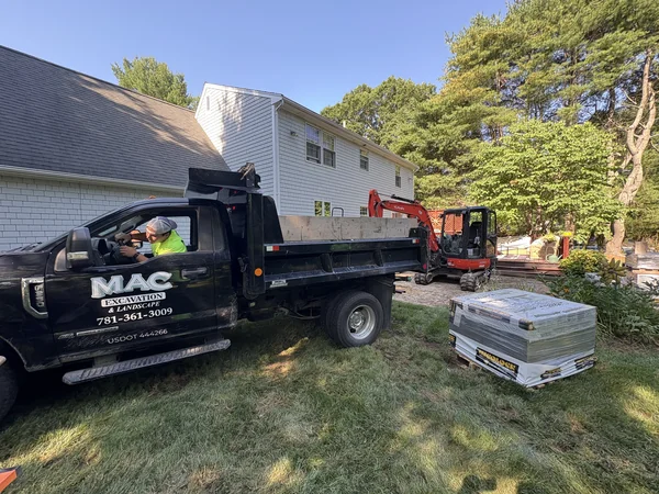 MAC Excavation & Landscape dump truck and mini excavator staged for hardscape construction at an East Bridgewater, MA home